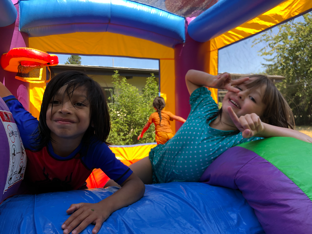 Two kids smiling while enjoying a bounce house